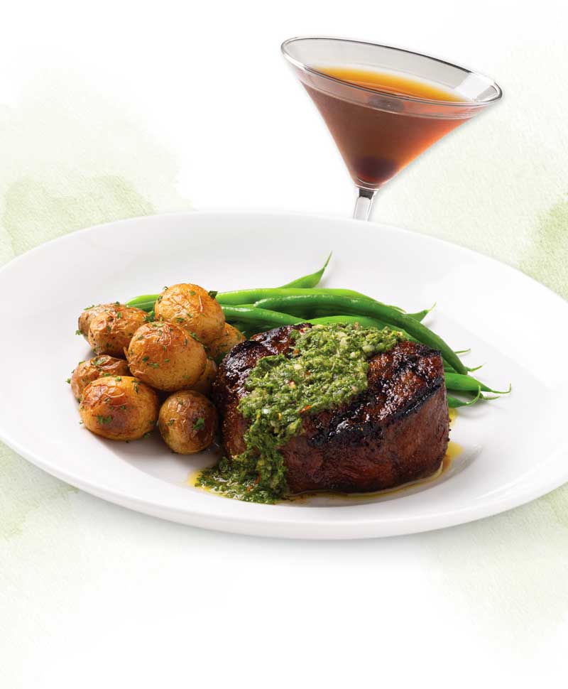 Seasons 52 Father's Day steak entrée featuring a wood-grilled Manhattan cut New York strip topped with chimichurri, marble potatoes, French green beans, and a classic Manhattan cocktail, served for a limited time.